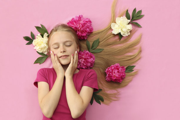一个拿着牡丹花的女孩，一头漂亮的金发，戴着五颜六色的儿童指甲图片下载
