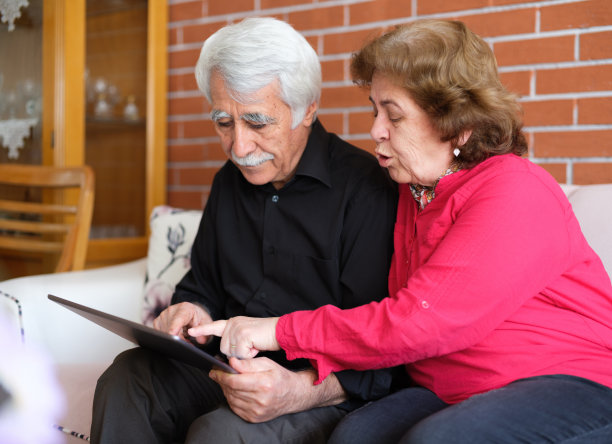 老年夫妇在家里使用数码平板电脑，大流行时期老年人网上购物的概念图片下载