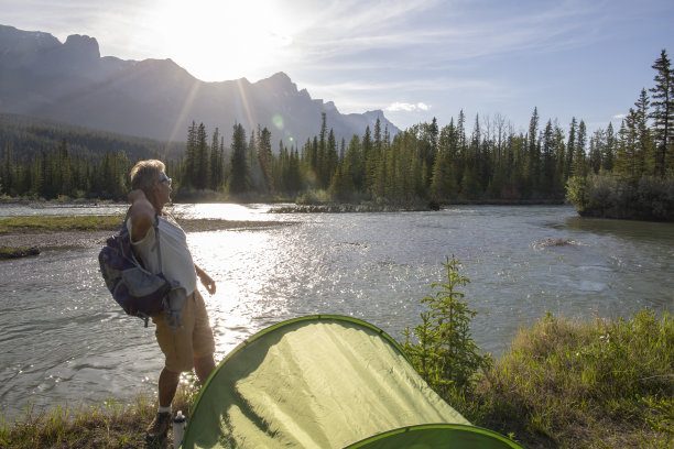 日出时分，徒步旅行者离开河岸上的营地图片下载