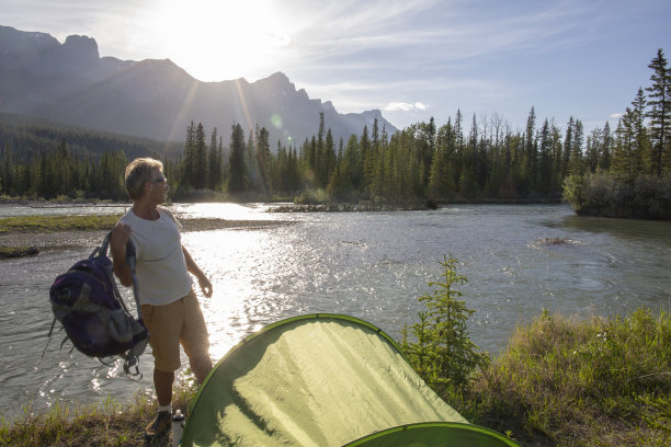 日出时分，徒步旅行者离开河岸上的营地图片下载