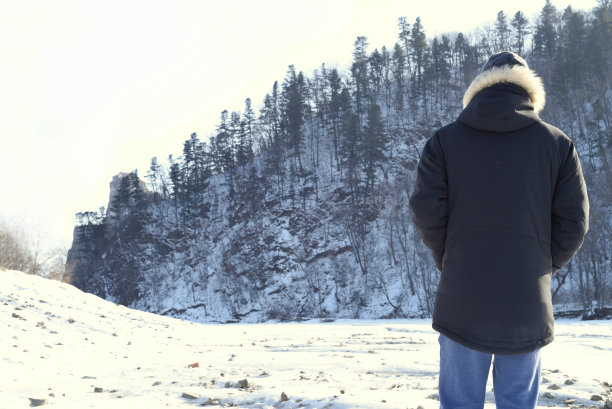 穿着暖和衣服的人站在森林里，看着雪山。冬天,俄罗斯。图片下载