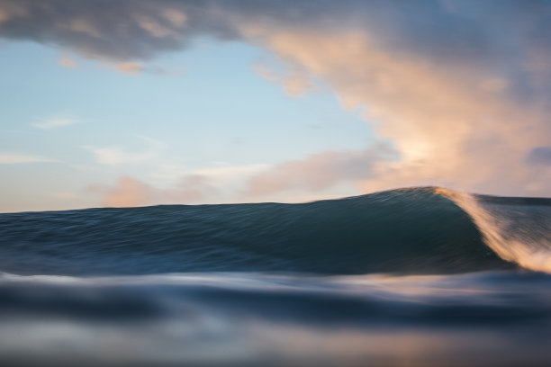 在粉红色天空的映衬下，浪花在海洋中劈开图片下载