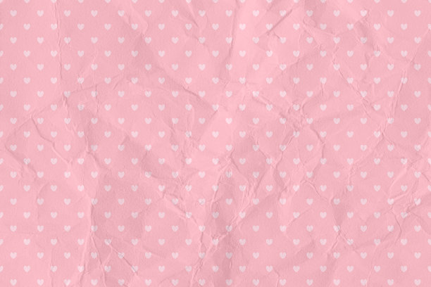 皱巴巴的粉色纸纹理背景，心形图案。情人节的背景概念图片下载