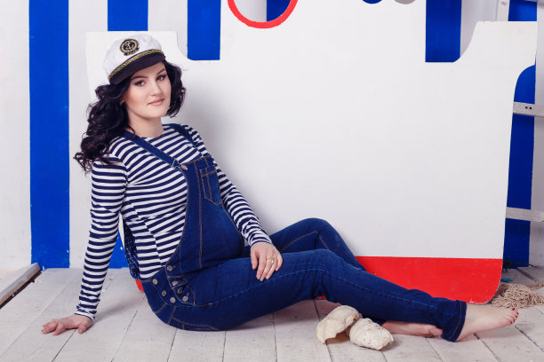 美丽的孕妇触摸她的肚子对着渔船和渔网。水手# 39;年代的妻子。图片下载