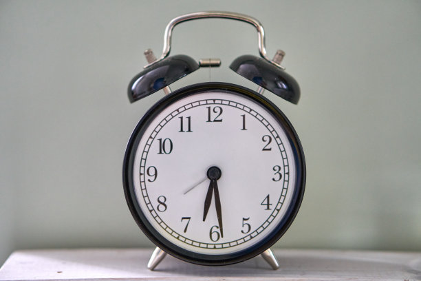 时间是早上5点半或下午5点半。复古时钟孤立木桌。5点半。图片下载