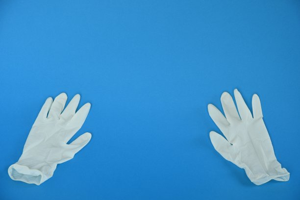 蓝色背景上的白色橡胶手套。图片下载
