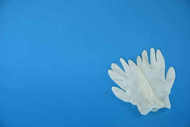 蓝色背景上的白色橡胶手套。图片下载