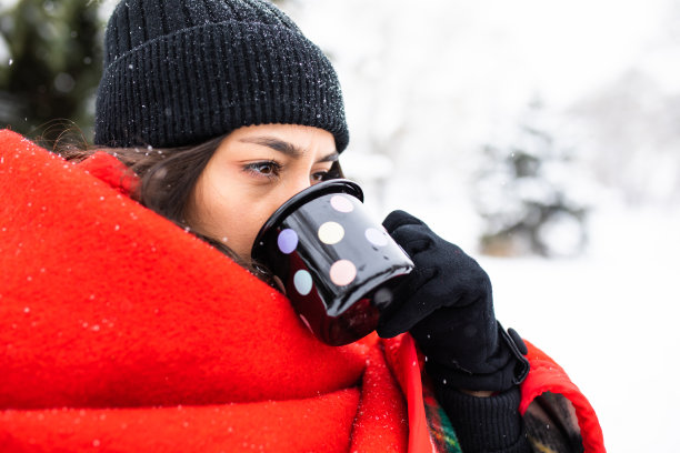年轻女人在雪地里户外喝茶图片下载