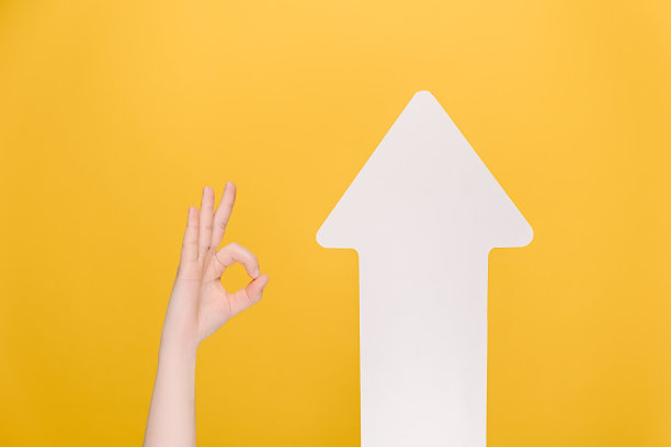 图片中一位不认识的女性在白色箭头附近竖起拇指，表示同意或同意，孤立在黄色背景上。肢体语言的概念。手的迹象。像手势图片下载