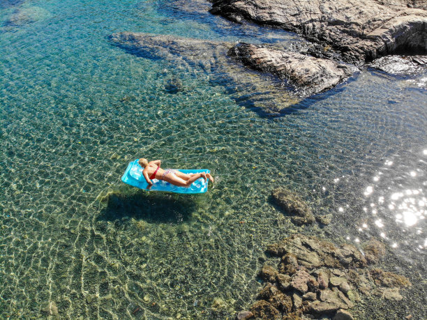 美丽的女人在海上的充气床垫上休息。图片下载