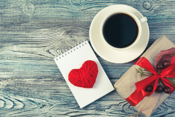 礼盒，记事本与一个心和一杯咖啡在一个灰色的蓝色木制背景图片下载