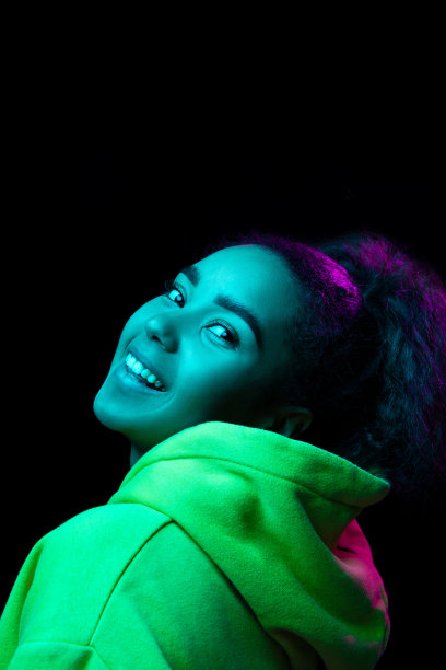 非裔美国妇女的肖像在彩色霓虹灯下被孤立在黑暗的工作室背景上图片下载