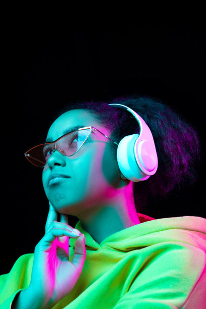 非裔美国妇女的肖像在彩色霓虹灯下被孤立在黑暗的工作室背景上图片下载