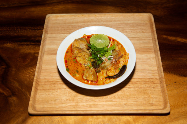 俯视图泰国北部食物(Khao Soi)，食谱咖喱面汤与鸡肉在一个碗在木制背景。图片下载