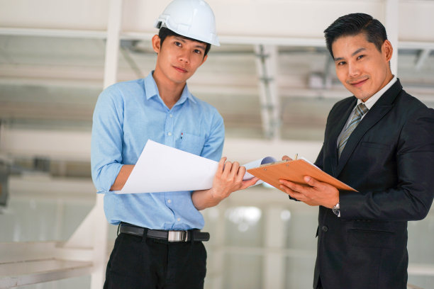 亚洲技术工程师戴着安全帽与西装革履的建筑业商人会面图片下载