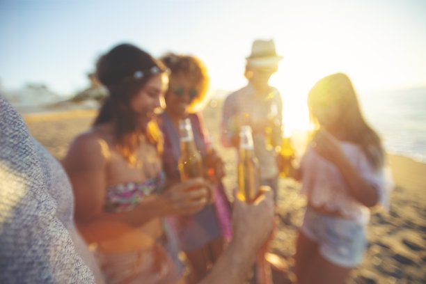日落时分，一群朋友在海滩上喝啤酒、跳舞。图片下载