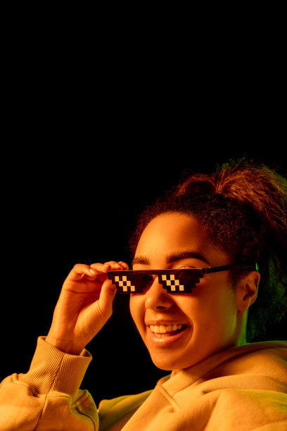 非裔美国妇女的肖像在彩色霓虹灯下被孤立在黑暗的工作室背景上图片下载