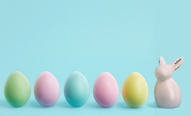 复活节快乐横幅。彩色的复活节彩蛋和兔子在蓝色的粉彩背景。复活节贺卡或带有拷贝空间的网页边框图片下载