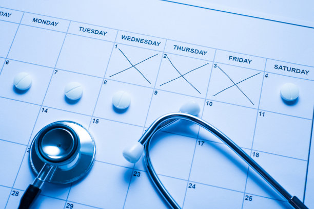 日历照片与交叉的地方和放置白色圆形药丸与听诊器图片下载