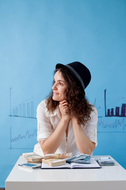 年轻的女士，坐在桌子上，面前放着一堆钱，在做梦图片下载