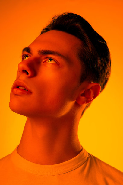 英俊的白人男子的肖像孤立在橙色的工作室背景霓虹灯，单色图片下载