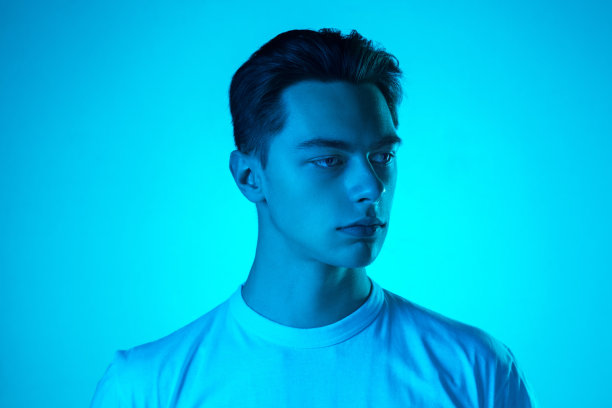英俊的白人男子的肖像孤立在蓝色的工作室背景霓虹灯，单色图片下载