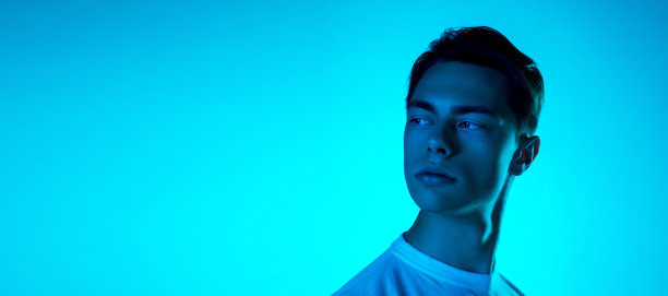 英俊的白人男子的肖像孤立在蓝色的工作室背景霓虹灯，单色图片下载