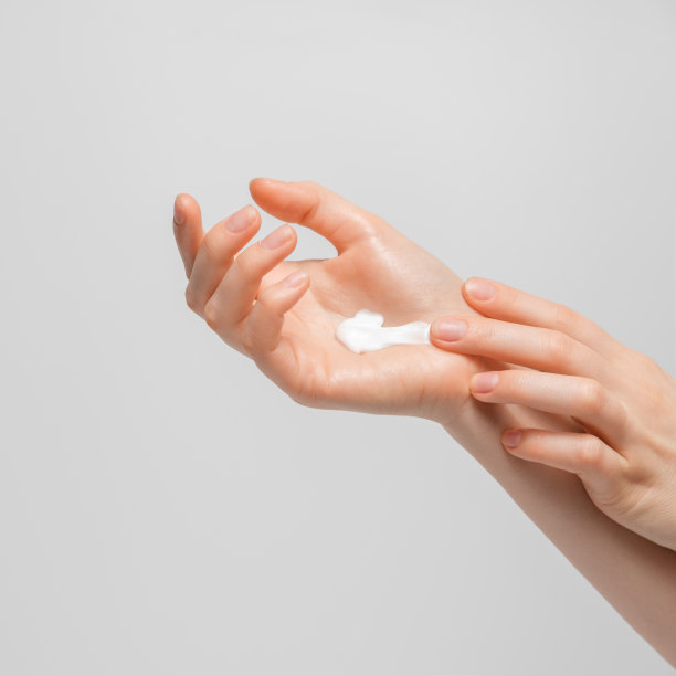 女人在手上涂有机乳霜的裁剪照片。年轻女子在涂护手霜。图片下载