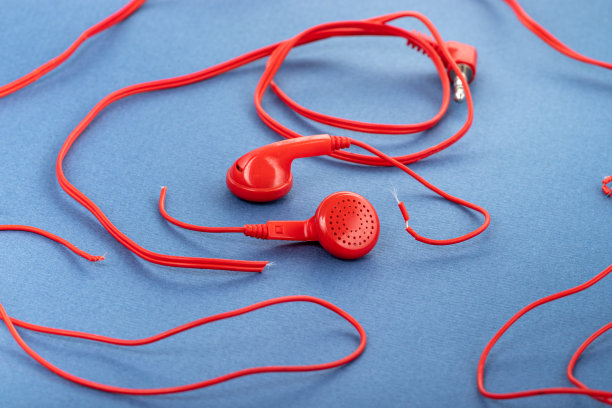 蓝色背景下的耳机。破耳机。修理电子设备。断丝。图片下载