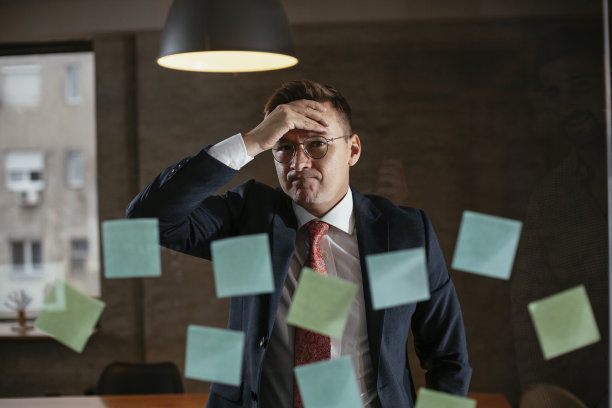 疲惫不堪的商人在会议室的玻璃墙上使用便利贴。T图片下载