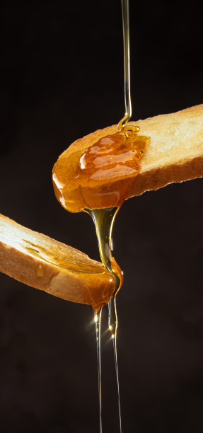 蜂蜜和吐司，美味的蜂蜜倒在吐司上，有选择的重点。图片下载