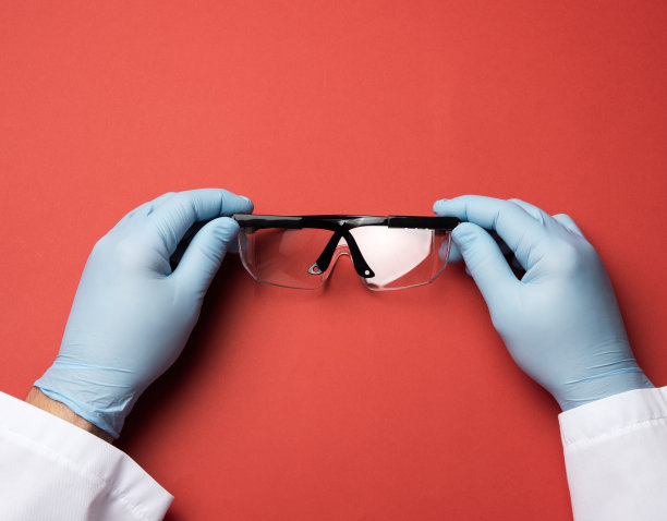 手持红色背景的塑料保护眼镜图片下载