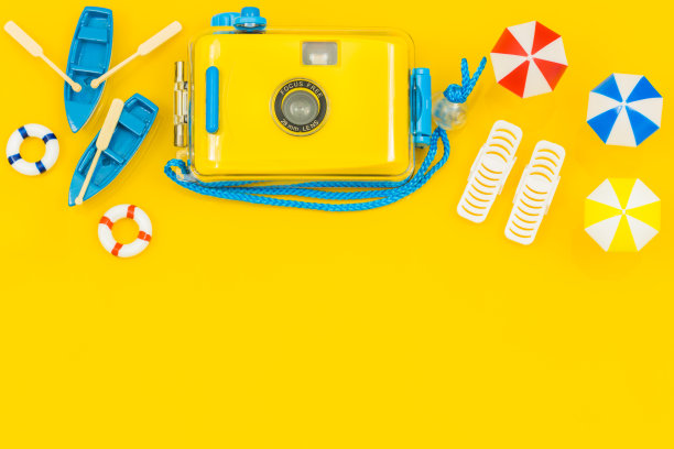 海滩设备的微缩模型和一个时髦的相机用于水下照片，雨伞，船，太阳躺椅。空白黄色背景与文字空间，概念，阳光海滩度假。图片下载