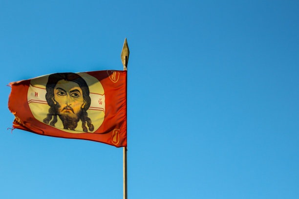 俄罗斯东正教教堂旗与图标，十字架和耶稣在风中飘扬的长矛对着蓝天。背景与复制空间的设计或文本图片下载