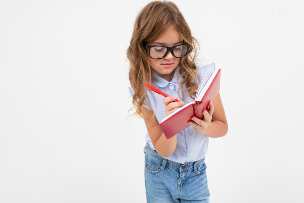 戴眼镜的聪明女孩在白色背景的笔记本上写字图片下载