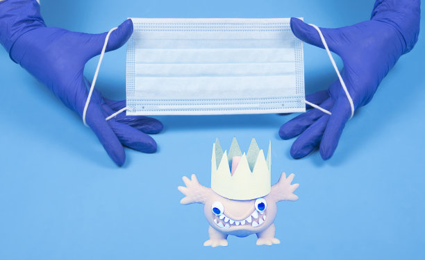 医生手拿医用口罩，蓝色背景顶视图冠状病毒图像，有拷贝空间。手在手套拿布口罩平与模型。图片下载