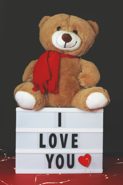 上面写着“我爱你”的灯箱和桌上的泰迪熊图片下载