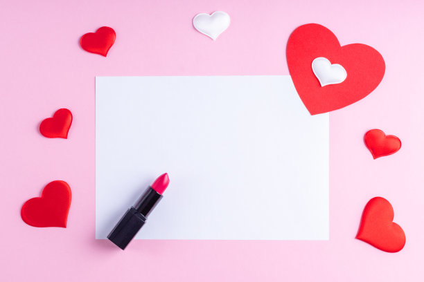 白色空白纸，红色口红和白色和红色心形在粉红色的背景。情人节的背景图片下载
