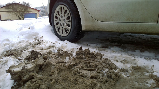 车轮脏脏脏的车停在雪地里。冬天路上有泥浆，盐和化学品。城市生态问题。保护和清洗车辆的概念。环境。开车。图片下载