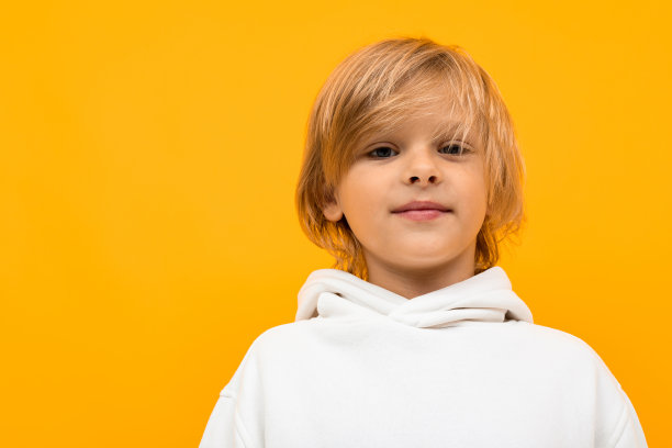 英俊的男孩在白色帽衫微笑和手势孤立在橙色背景图片下载