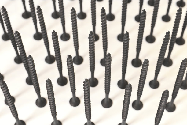 自攻螺钉用于木材表面，站在帽子上，在光线背景上。用于建造和维修的部件。金属紧固件。图片下载