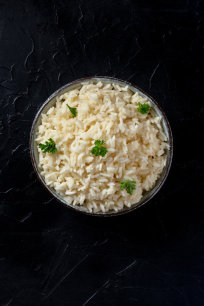 白米，煮熟，与欧芹，上方拍摄的黑色背景图片下载