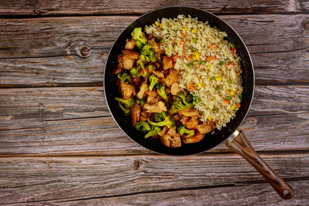 以木为背景，用平底锅炒鸡、西兰花和米饭。图片下载