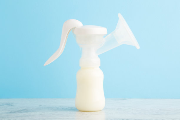 塑料吸乳瓶放在木桌上，浅蓝色的墙壁背景。柔和的颜色。特写镜头。前视图。准备给婴儿喂奶。图片下载