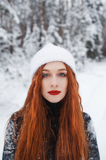 年轻的红头发女孩与长长的红头发在冬季的背景。睫毛上的雪花，一个大女孩的肖像。图片下载