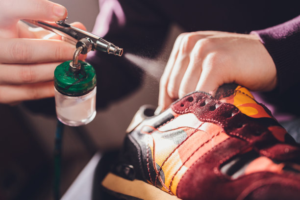 工匠画在一双鞋上。粉刷和修复绒面革运动鞋。图片下载