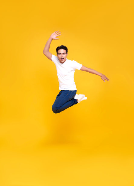 年轻快乐英俊的亚洲男子跳孤立的黄色背景。图片下载