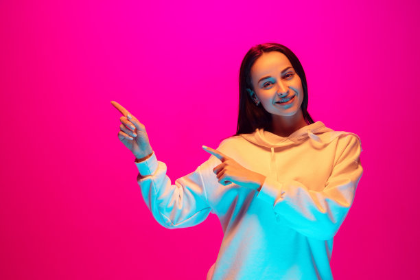 白种人美丽的女人的肖像孤立在粉红色的工作室背景在五颜六色的霓虹灯图片下载