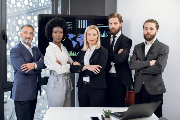多种族关注的成功多样化的男性和女性员工团队的正面视图，站在镜头前，双臂交叉在现代会议室的大屏幕后面图片下载