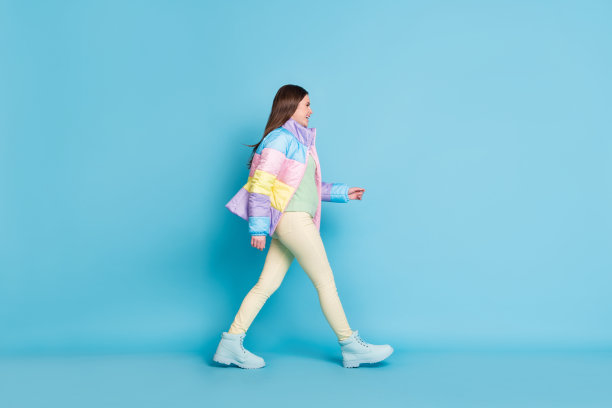 照片肖像全身侧面的女人行走孤立在柔和的蓝色背景图片下载